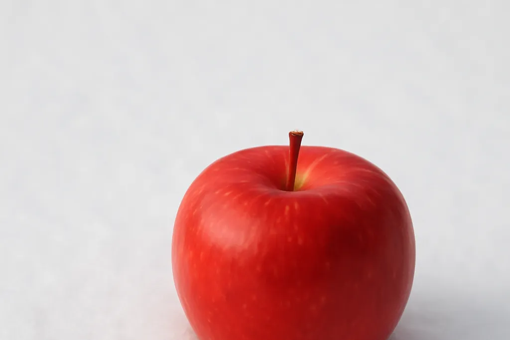 Pomme rouge posee sur de la neige fraiche, contraste de couleurs vives sur fond blanc